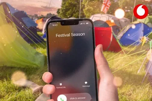Person holding an iPhone 12 at a festival campsite